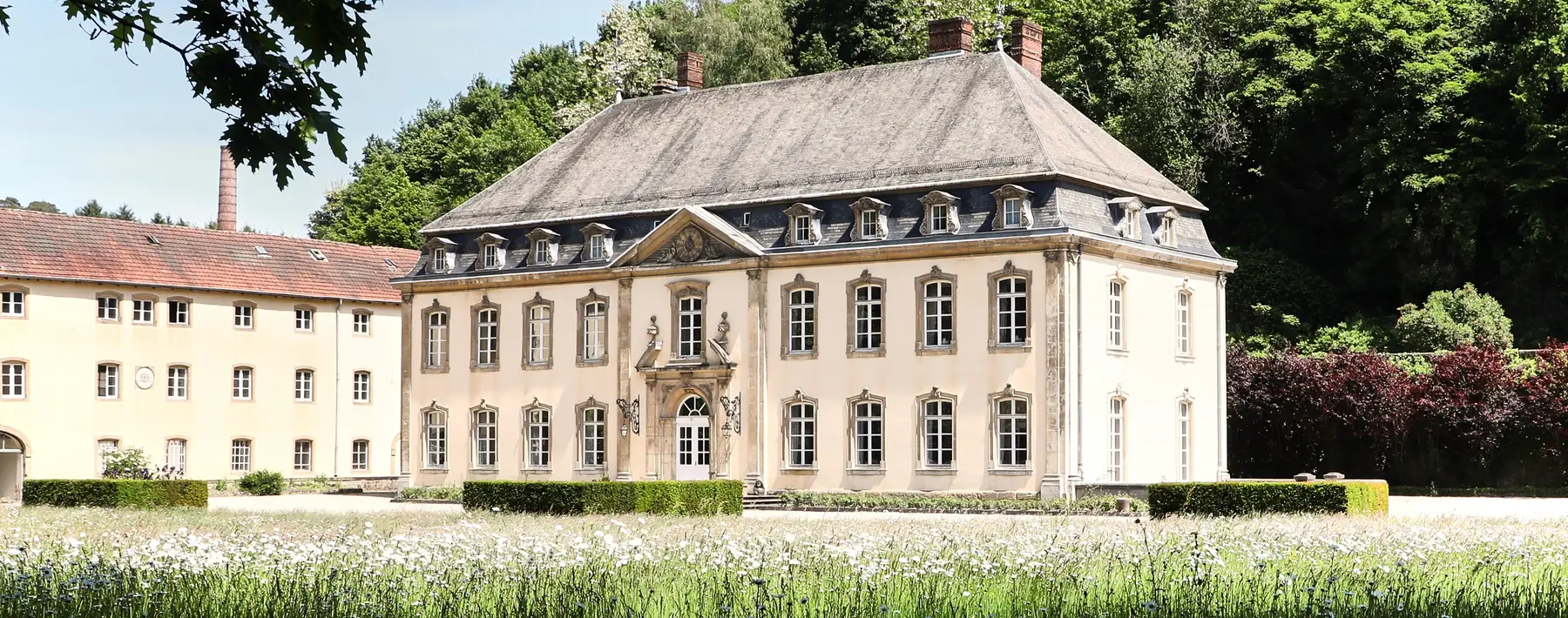 The Château de Septfontaines in Luxembourg in early summer, behind a meadow in flower