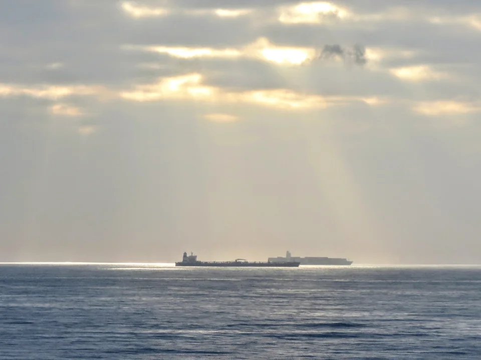 A tanker on the horizon at sunrise, waiting at sea